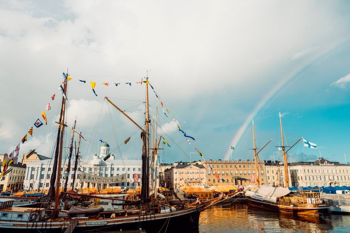 Helsingin satama, purjelaivat liputettuina ja sateenkaari taivaalla.