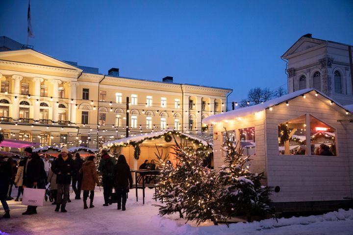 Kuva Tuomaan Markkinoilta: luminen tori täynnä joulumyyntikojuja ja ihmisiä.