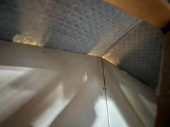 Kuva ullakolta, missä näkyy palo-osastoiva seinä ja valon loistaminen ruoteiden välistä.