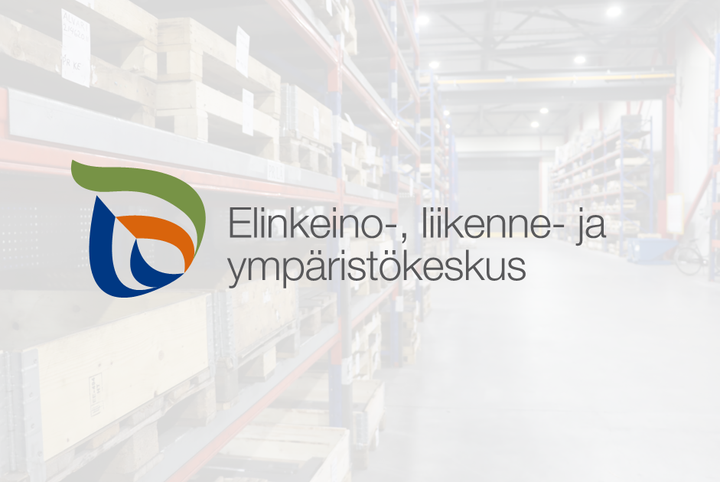 Elinkeino-, liikenne- ja ympäristökeskuksen logo vaalealla taustalla, jonka takaa näkyy tehtaan käytävä, jossa hyllyjä.