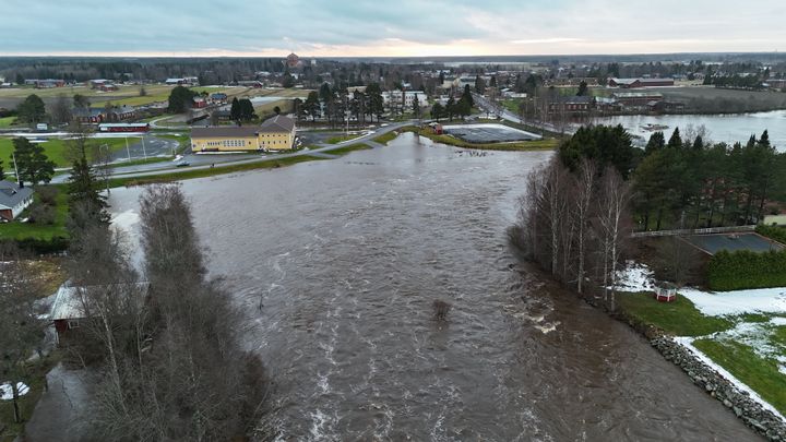 Ilmakuva, jossa näkyy miten vesi on tulvinut pellolle ja tielle.