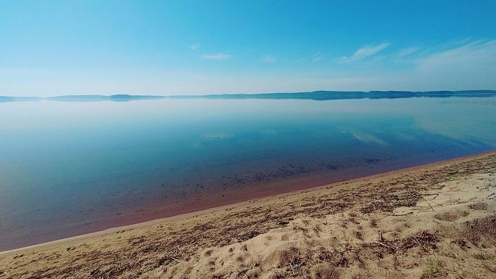 Kuva Immalanjärvestä: tyyni järvi ja hiekkaranta. Taustalla metsää ja sininen taivas.