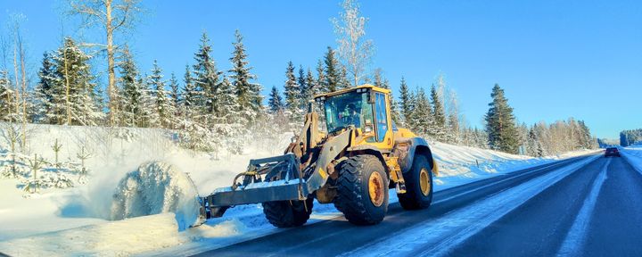 Urakoitsija leikkaa lumivalleja tien reunalta Rautjärvellä kirkkaassa talvisäässä.