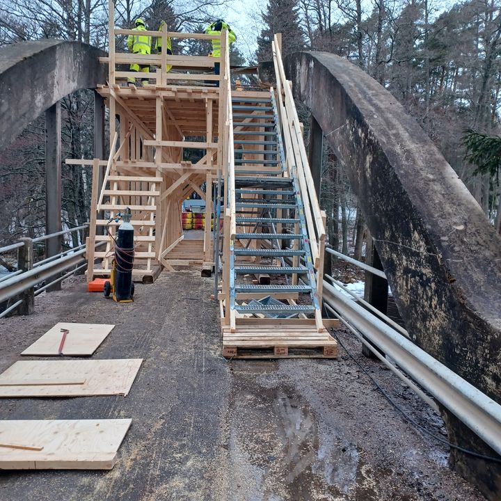 Den träställning som användes vid reparationen av bron, med arbetare ovanpå den.