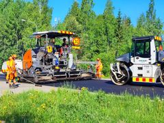 Päällystystyömaa, jossa asfalttikone ja jyrä työskentelevät tiellä Hämeenlinnassa, toukokuu 2024. Työntekijöitä näkyy koneiden lähellä.