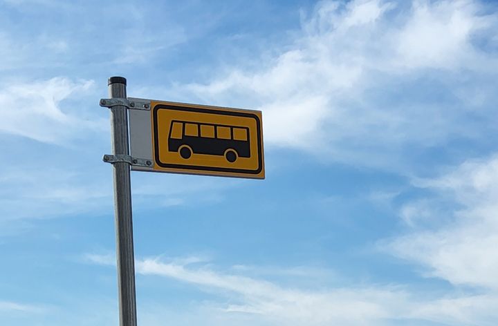 Keltainen bussipysäkkikyltti, taustalla sininen taivas.