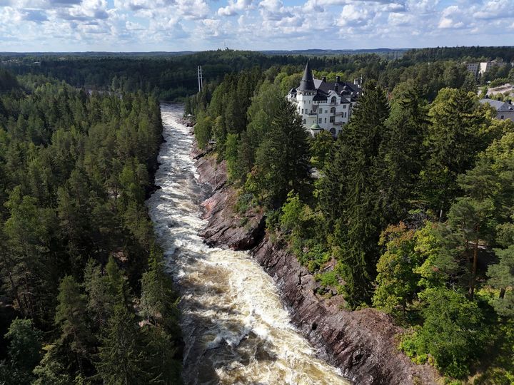 Ilmakuva Imatrankoskesta, ympärillä metsää ja historiallinen rakennus.