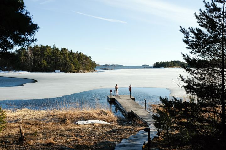 Rannasta sula järvi, laituri, jolla seisoo uimari.