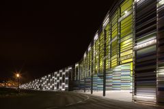 Ulkokuva Merikeskus Vellamosta, jonka julkisivu koostuu värikkäistä, valaistuista paneeleista. Näkymä on illalla, ja katuvalaistus on päällä.