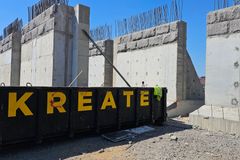 Rakennustyömaa, jossa näkyy keskeneräisiä betonielementtejä ja metallinen kontti, jossa lukee "KREATE".