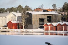 Talvisessa kuvassa keskellä esiintyy harmaan sävyinen moderni puutalo, PAVE Studio, jossa on harjakatto ja kaksi neliönmuotoista aukkoa näkyvässä kyljessä. Rakenus asettuu joen varteen, naapuritalona on selvästi vanhempi yli satavuotias vaalenaharmaa harjakattoinen koulurakennus. Kuvassa näkyy myös punaisia venevajoja. Modernin rakenuksen edessä on veistoksellinen puu ilman lehtiä.