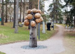 Naistenklinikan veistospuisto, etualalla Pasi Karjulan ”Puupallopuu”, 2019, lehtikuusi, korkeus 300 cm, taka-alalla Veikko Nuutisen teoksia.