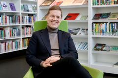 Timo Järvensivu sitter i en grön stol framför bokhyllar.