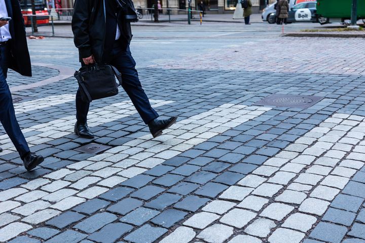 Kaksi pukupukuista henkilöä kävelemässä suojatiellä kaupunkialueella.