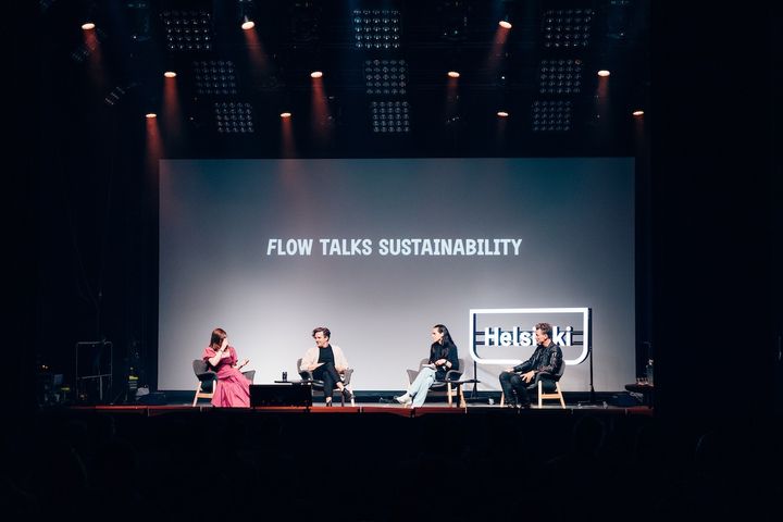 Henkilöitä istumassa esiintymislavalla, taustalla lukee Flow Talks Sustainability.