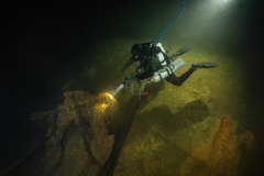 A diver examines the anchor of the coastal defense ship Ilmarinen with a trawl net caught in the wreck.