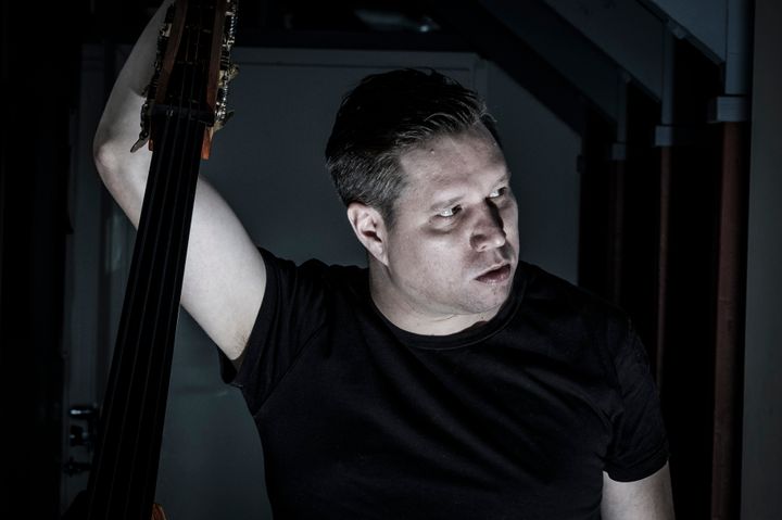 Bassist Antti Lötjönen photogaphed in front of dark background.