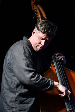 Bassist Antti Lötjönen performing on stage.