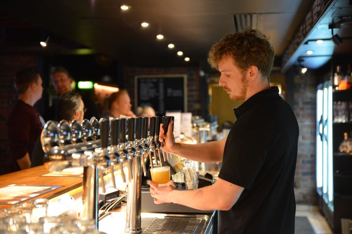 An employee is pouring beer from the tap into a glass