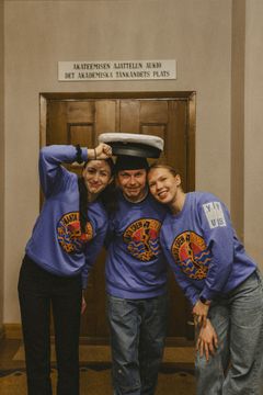 Manta Crew'n Julia Gunyhó, Vertti Perttilä ja Janita Malinen poseeraavat hymyillen Mantan lakin kanssa.