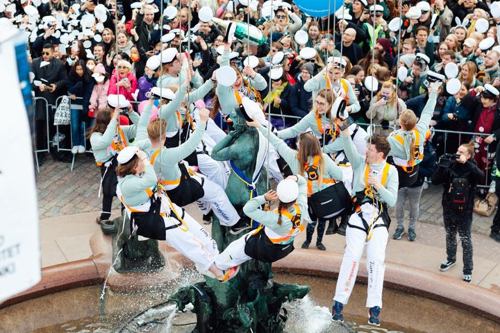 Nosturista roikkuvat opiskelijat asettavat Havis Amanda -patsaan päähän ylioppilaslakin.