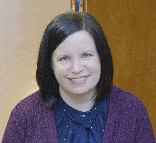 Tummatukkainen nainen hymyilee kameraan.