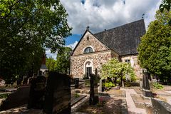 Esbo domkyrka som är en gråstenskyrka fotograferad i sol och lummig grönska.