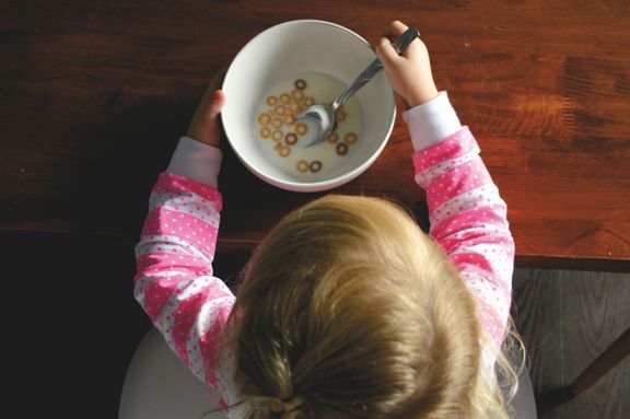 Ett litet barn sitter med en skål mat framför sig.