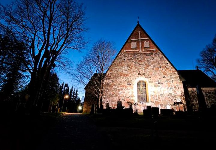 En upplyst stenkyrka mot en djupblå grund.