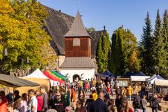 Ett folkmyller på marknad intill Esbo domkyrka och kyrkans klockstapel i soligt höstväder.