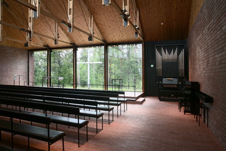 En kyrksal i modern avskalad stil med fönster ut mot naturen som fungerar som altartavla.