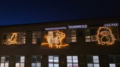 Rakennuksen seinällä on valokoristeita: kolme pöllöä, orava ja siili.