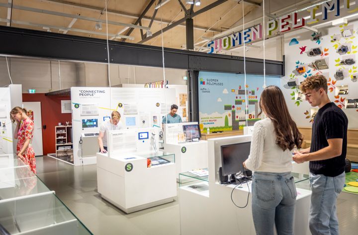 Museokävijöitä tutkimassa näyttelyn esineitä Suomen pelimuseossa.