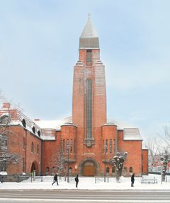 Punatiilinen Paavalin kirkko Tartossa talvisessa maisemassa. Etualalla kävelee useita ihmisiä.