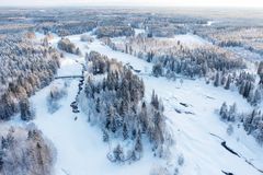 Ilmakuva talvisesta Koitelinkoskien metsän ympäröimästä maisemasta.