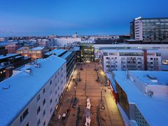 Ilmakuva Oulun keskustasta iltahämärässä, katuvalot loistavat lumisten rakennusten keskellä.