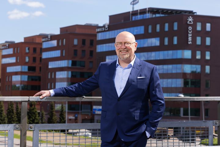 Thomas Hietto in a suit standing outdoors in front of an office building.