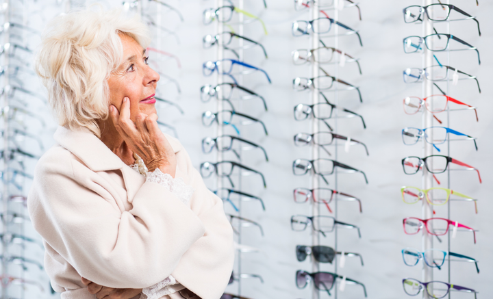 Nainen katselee silmälasivalikoimaa optikkoliikkeessä.