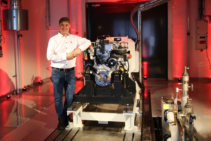 AGCO Power's Director of Engineering Kari Aaltonen in front of a hydrogen combustion engine in the new Clean Energy Laboratory.