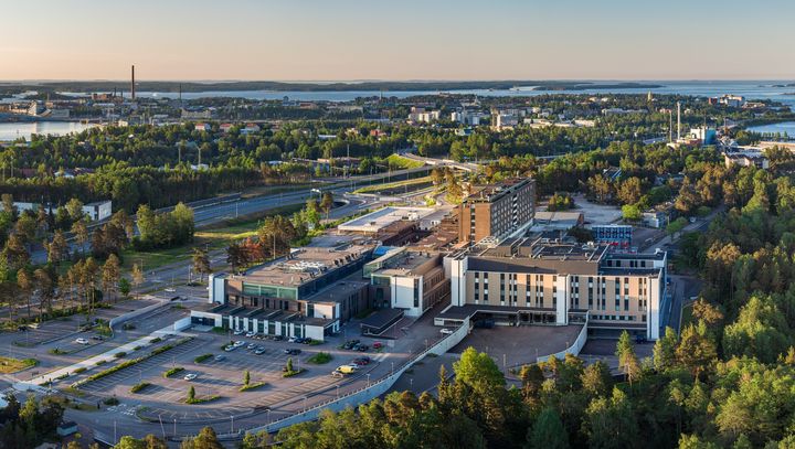 Ilmakuva Kymenlaakson keskussairaalan rakennuskompleksista vehreän maarannan ja vesistöjen läheisyydessä.