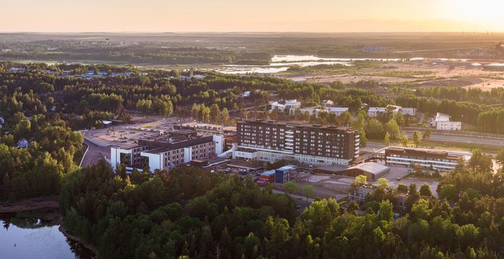 Ilmakuva laajasta, vehreästä alueesta, jossa on keskellä Kymenlaakson keskussairaala auringonnousussa.