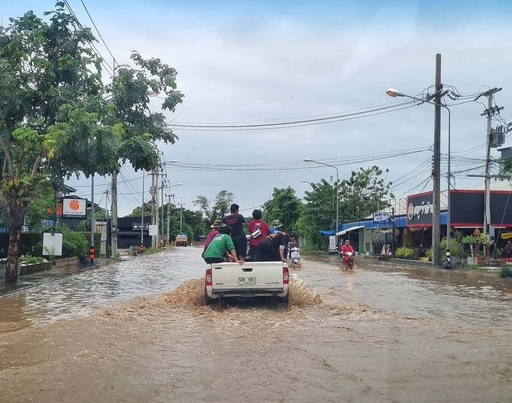 Tulvivalla kadulla ajaa auto, jonka takalavalla on nuoria