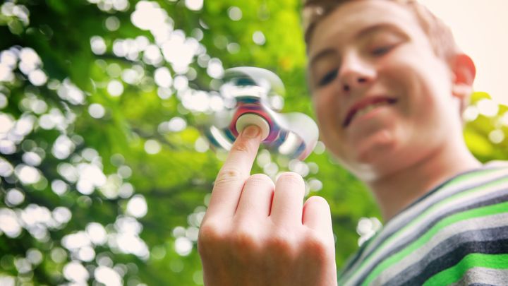 Hymyilevä poika pyörittelee fidget spinneriä