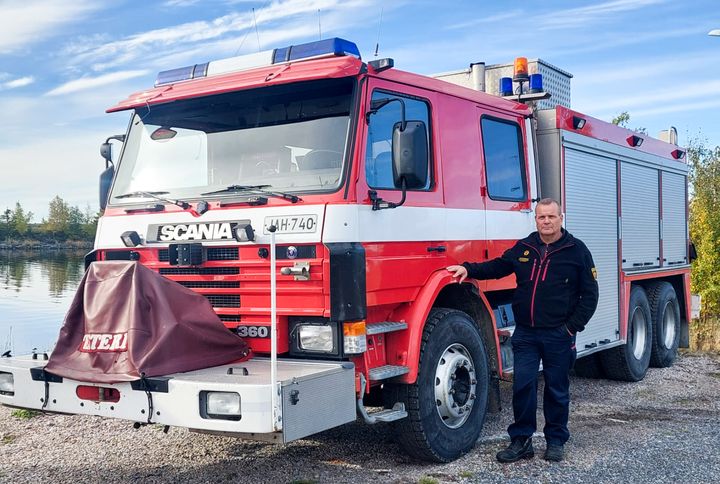 Sammutusauto ja pelastuslaitoksen työasuun pukeutunut mies.