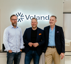 Kolme miestä seisoo vierekkäin Voland Partners Oy:n logon edessä.