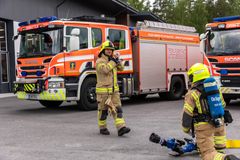 Paloauto Orimattilan tunnuksella sekä kaksi pelastajan varusteissa olevaa palomiestä harjoittelemassa.