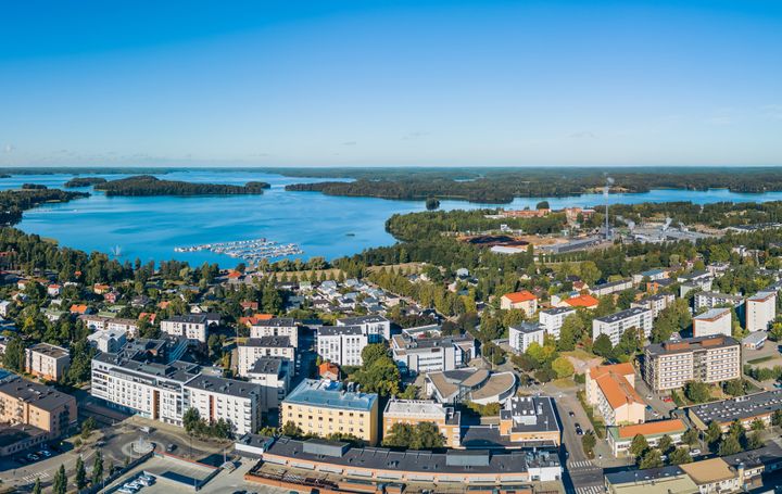 Ilmakuva Lohjan kaupungin keskustasta järven rannalla, paljon rakennuksia ja vehreyttä.