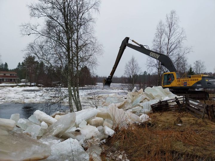 Kone purkaa jääpatoa joella.