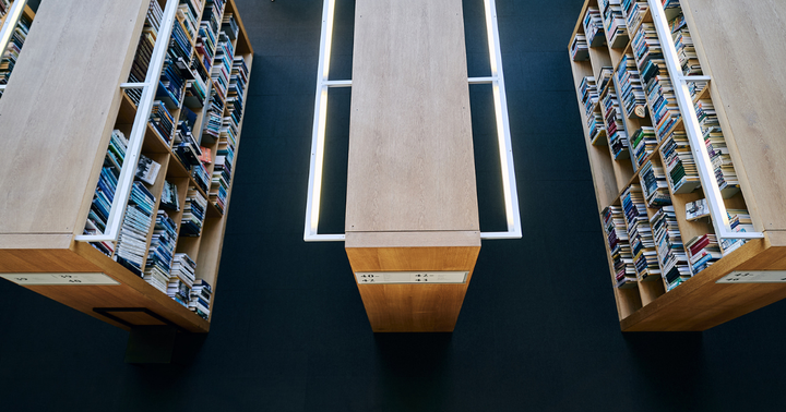 Kolme suurta kirjahyllyä kuvattuna ylhäältä päin, täynnä erilaisia kirjoja.